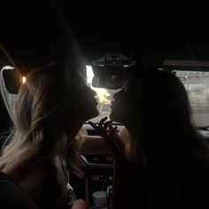 two women sitting in the back seat of a car