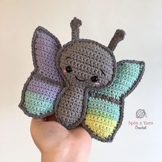 a crocheted stuffed animal in the shape of a butterfly is held by a person's hand