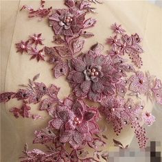 the back of a woman's dress with pink flowers and pearls on top of it