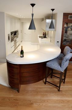 a kitchen with an island and bar stools in the center, surrounded by wooden floors