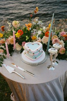 a heart shaped cake sitting on top of a table next to flowers and silverware