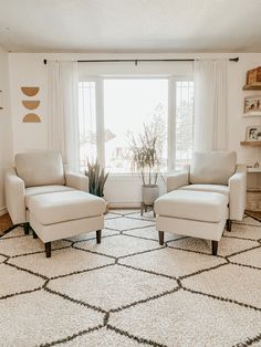 a living room with two white chairs and a rug in front of a large window