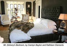 a bed with white sheets and pillows in a bedroom next to a table with two lamps on it