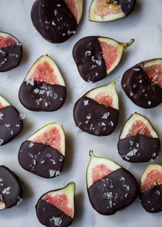 chocolate covered figs are arranged on a white surface