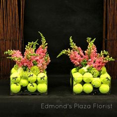 two vases with tennis balls and flowers in them on a black tablecloth background