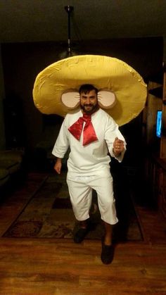 a man wearing a large yellow hat and red bow tie, standing in a living room