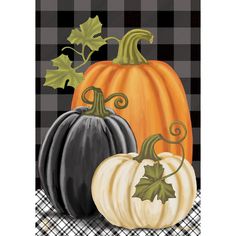 three pumpkins on a plaid table cloth