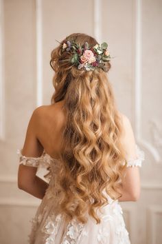 the back of a woman's head with long hair and flowers in her hair