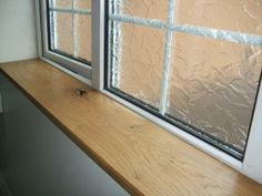 an empty window sill in front of a wooden counter with plastic covering on it