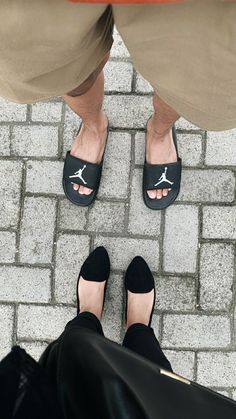 two people standing next to each other with their feet up on the ground wearing black shoes