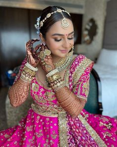 a woman in a pink and gold bridal outfit holding her hands to her face