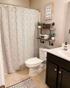 a white toilet sitting next to a bathroom sink under a shower curtain in a bathroom