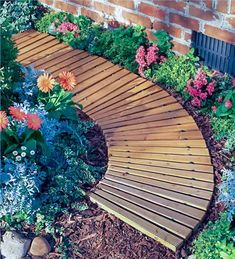 a wooden bench sitting next to a brick wall in a flower bed filled with flowers