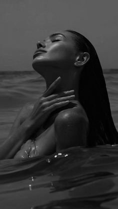 a woman is floating in the ocean with her hands on her chest and eyes closed