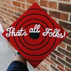 a red cap with the words that's all folks on it is held up against a brick wall