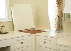 the corner of a kitchen with white cabinets and drawers