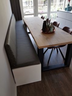 a wooden table sitting next to a window in a room with wood flooring and white walls