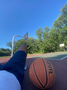 a basketball sitting on the ground next to a person's feet with their legs in the air