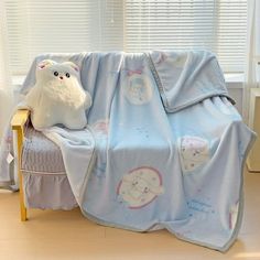 a white stuffed animal sitting on top of a bed next to a blanket and pillow