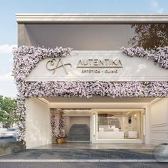 the entrance to an upscale shopping center with purple flowers growing on the building's facade