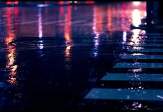 an image of rainy night scene with street lights and crosswalk in the foreground