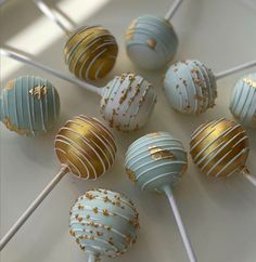 there are many blue and gold cake pops on the table