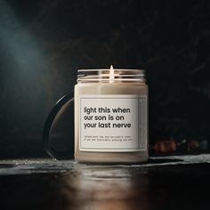 a candle with a quote on it sitting on top of a table next to a wall