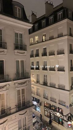 an aerial view of a building at night with people walking on the sidewalk and cars parked in front