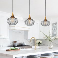 three pendant lights hanging over a kitchen island