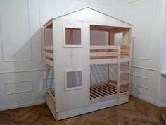 a wooden bunk bed in a room with white walls and wood flooring on the side