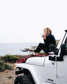 a woman sitting on top of a white jeep