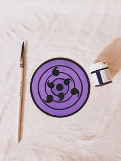 a purple circle with black dots on it next to a paintbrush and an acrylic tube