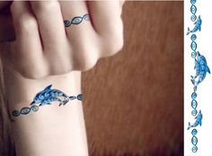 a woman's hand with a blue dolphin tattoo on her left wrist and an ocean themed band around the wrist