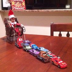 an elf is sitting in a stroller with cars on the table next to him