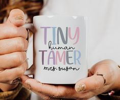 a woman holding a coffee mug with the words tiny human tamer on it