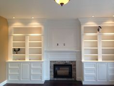 a living room with white bookcases and a fire place in the middle of it