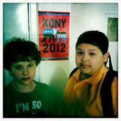 two young boys standing next to each other in front of a poster on the wall