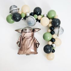 a star wars balloon garland with a baby yoda in the center and balloons around it