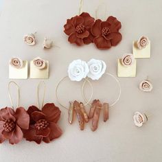 several different types of flowers and earrings on a white surface with gold tags attached to them