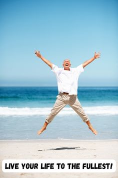 a man is jumping in the air at the beach with his arms wide open and hands out