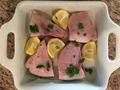 meat with lemons and parsley in a white casserole dish