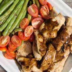 chicken, asparagus and tomatoes on a white plate