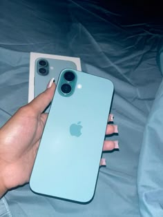 a person holding an iphone in their left hand next to the case on her bed