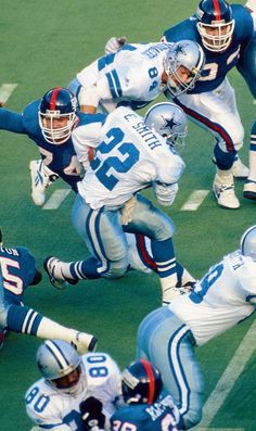 a group of football players on a field playing with each other and running for the ball