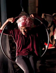 a woman with pink hair is riding on a hoop