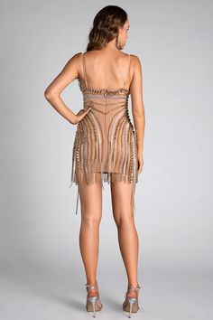 the back of a woman wearing a short dress with fringes and beads on it