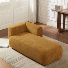 a yellow couch sitting on top of a wooden floor next to a white table and chair