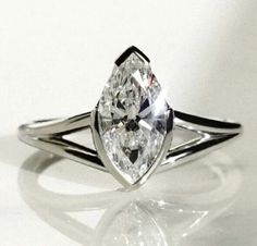 a pear shaped diamond ring sitting on top of a white surface