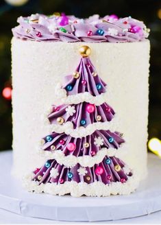 a white cake with purple icing and a christmas tree decoration on it's side