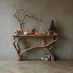 a wooden table with candles and ornaments on it in front of a gray wall that has a tree